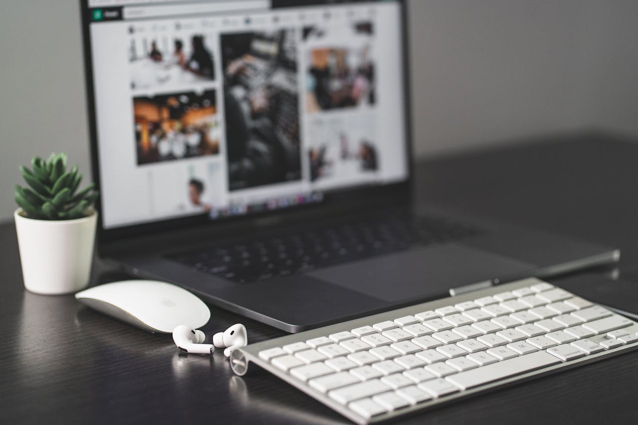 about-01 A sleek modern workspace featuring a laptop, keyboard, mouse, AirPods, and a small plant.